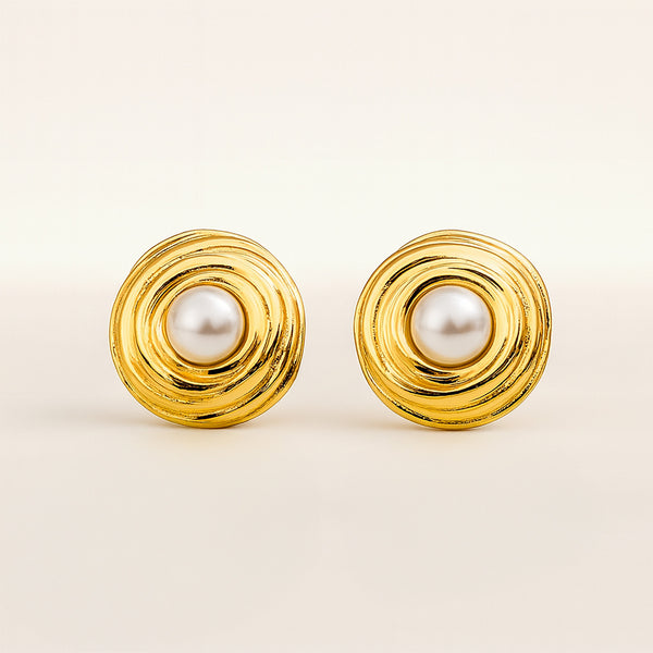 Pair of gold earrings with pearl centers on a beige background