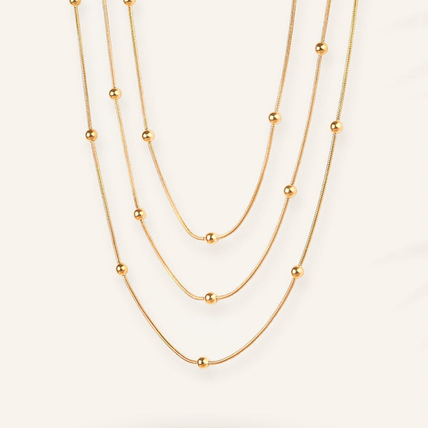 Three gold necklaces of different lengths on a white background